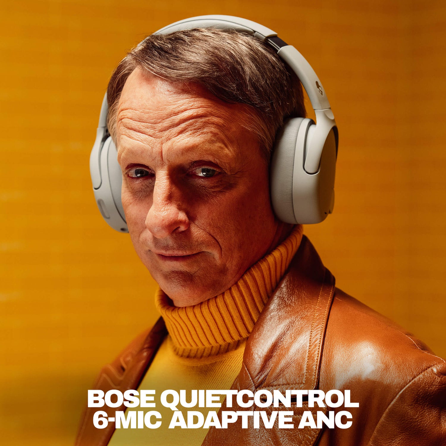 TOny Hawk wearing Skullcandy headphones with QuietControl with a warm background | Cement