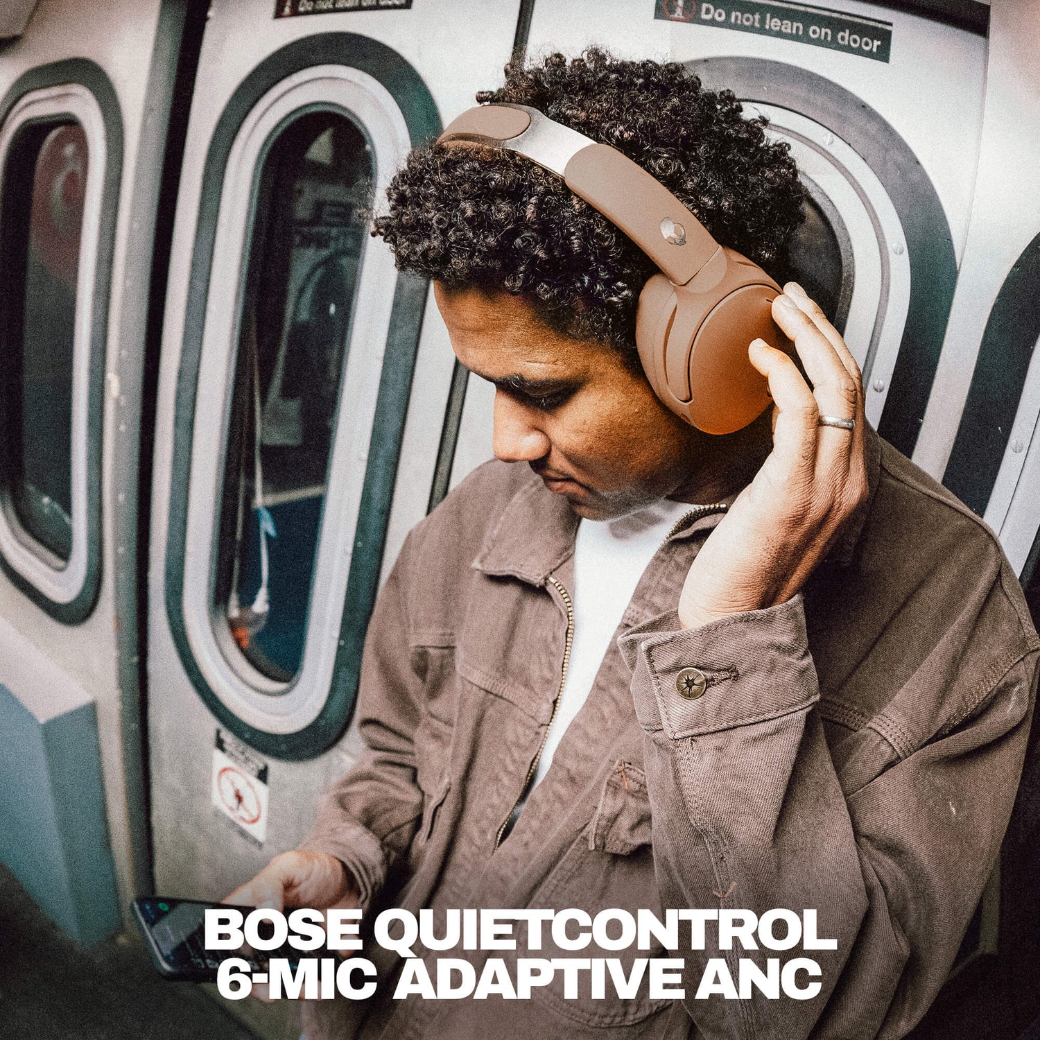 Person wearing Skullcandy Headphones with Bose QuietControl on a subway train, with product name displayed. | Primer
