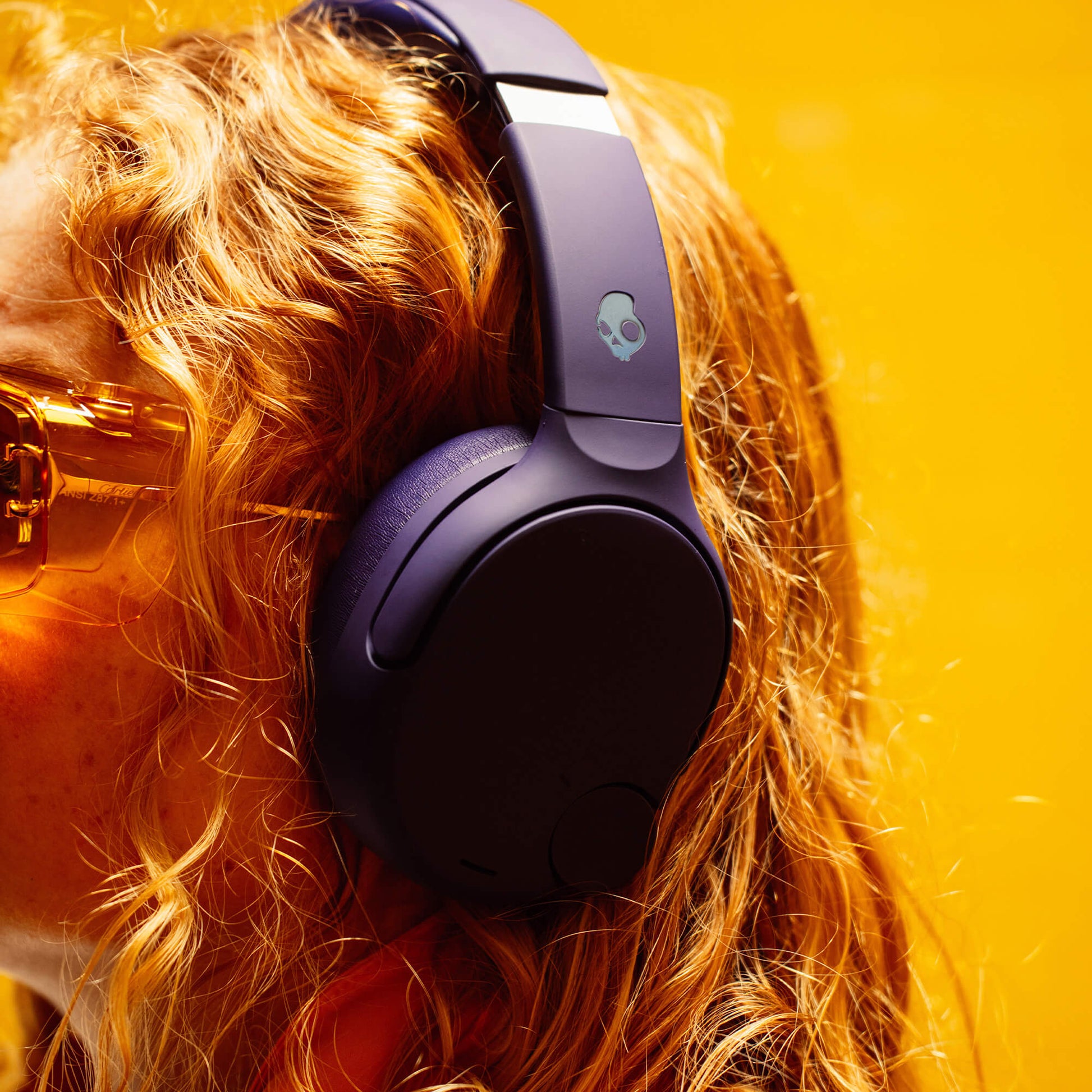 Person wearing purple Crusher 720 headphones with a skull logo on a bright yellow background | Future