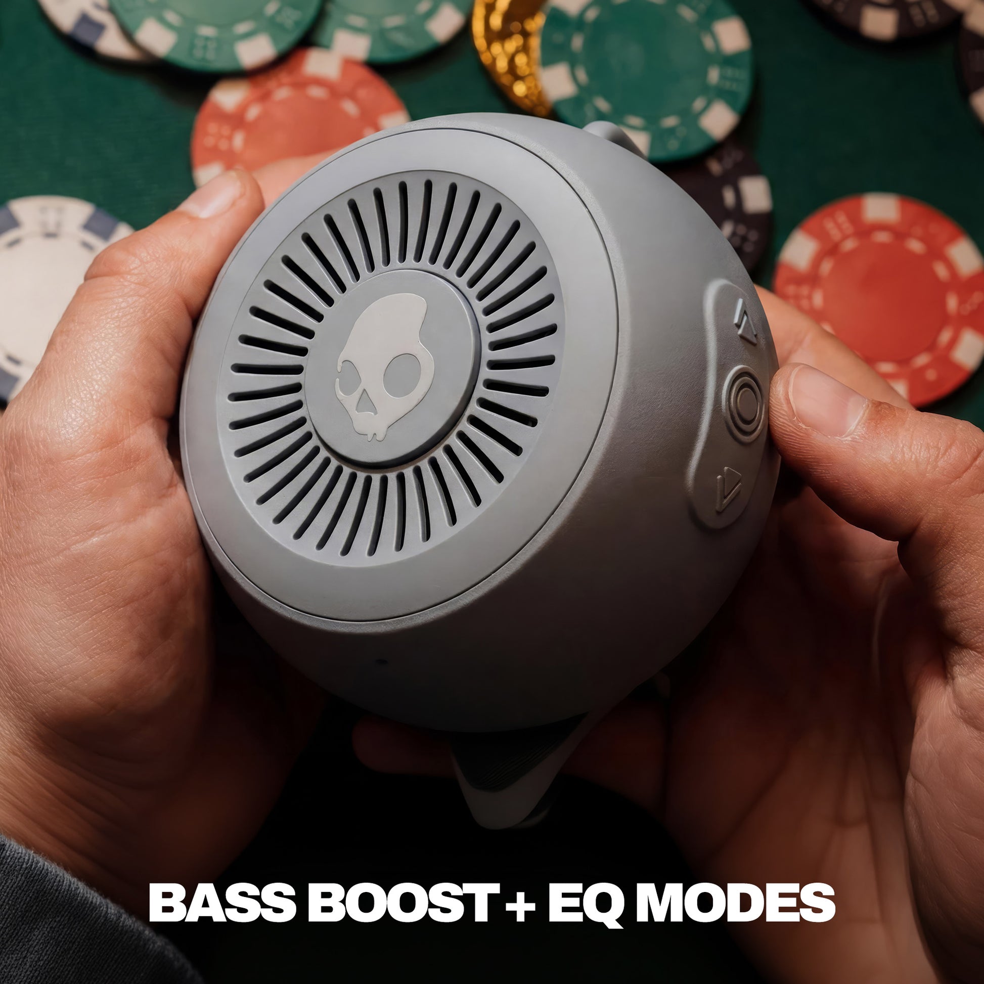 Person holding a gray speaker with poker chips in the background | Cement