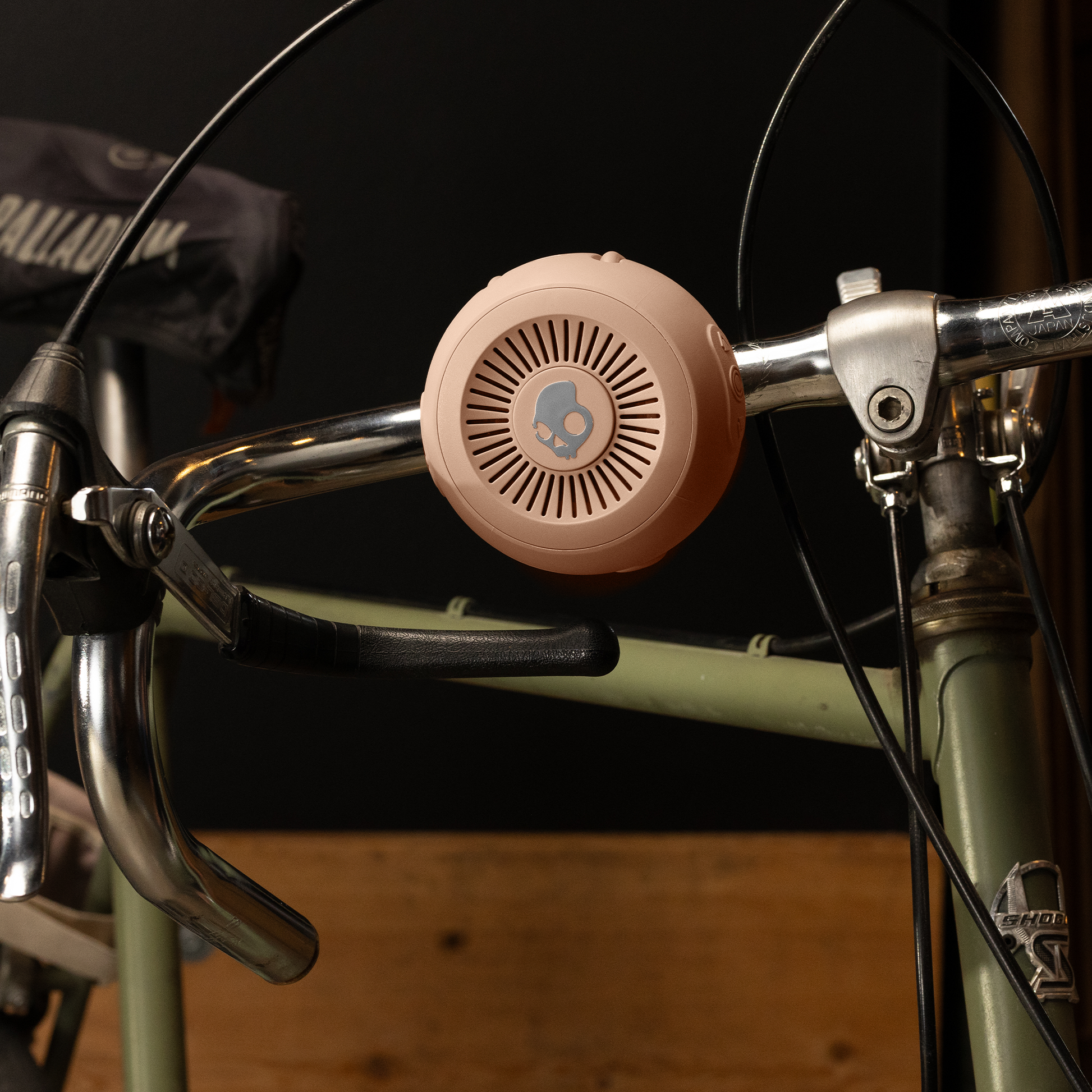 Pink bicycle bell attached to a bike handlebar with a dark background | Primer