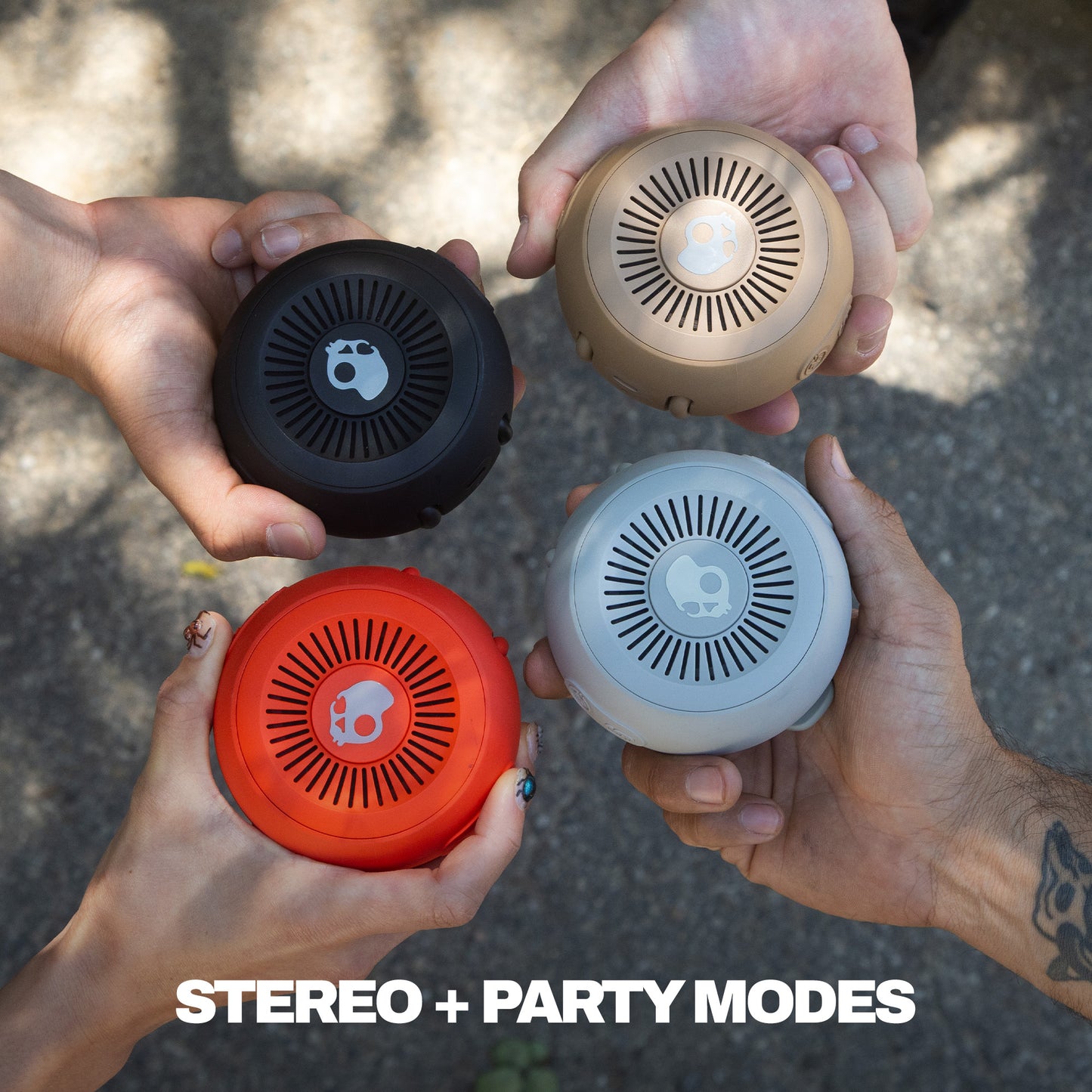 Four hands holding different colored round speakers with 'STEREO + PARTY MODES' text. | Primer
