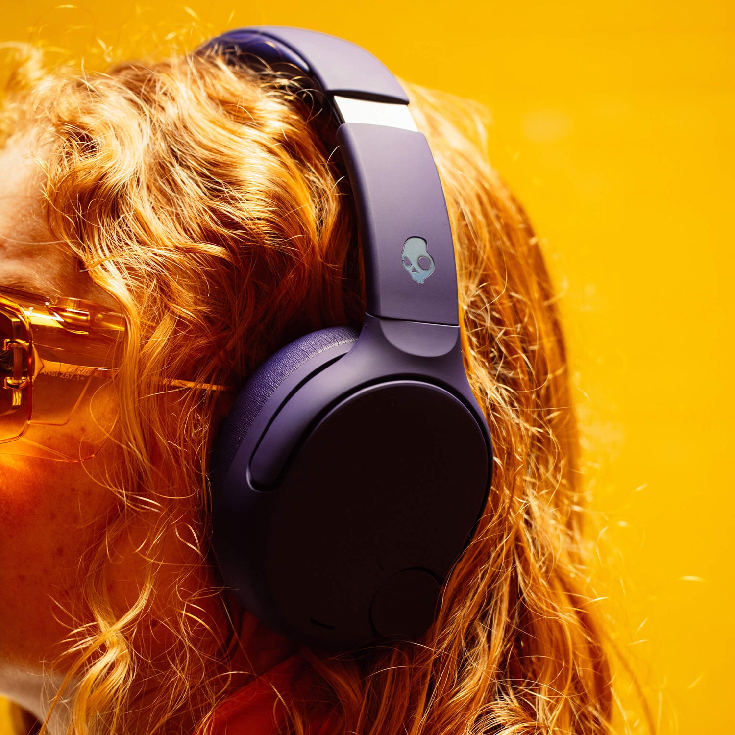 Person wearing purple Crusher 720 headphones with a skull logo on a bright yellow background | Future